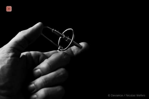 Fotografía en blanco y negro de una mano sosteniendo un cetro de príncipe metálico, una varilla corta con un aro