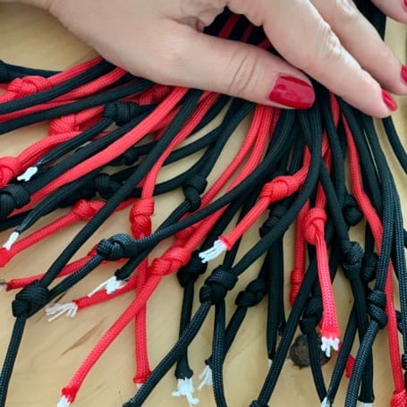 Los extremos de los cordones de paracord negros y rojos anudados uno a uno y extendidos sobre la mesa