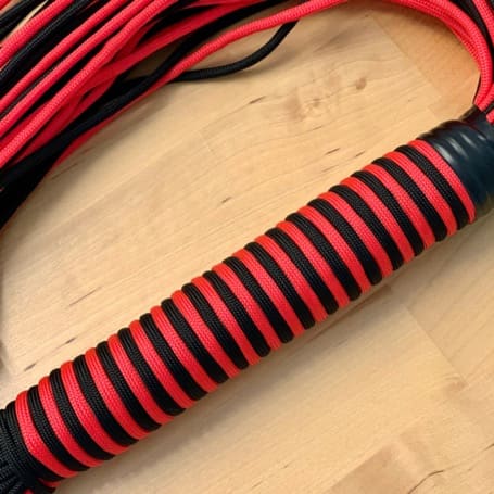 Mango del flogger terminado con anillos negros y rojos uniformes, con las tiras detrás