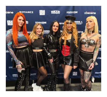 Cinco personas con conjuntos de cuero y látex posando juntas ante el muro de patrocinadores de Obscene 2025