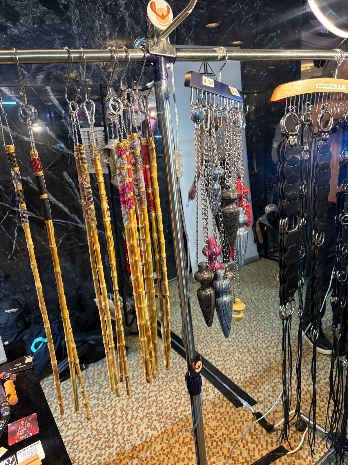 Expositor en Venus 2025 con collares de cuero, cadenas, juguetes de madera torneada y varas con mangos cubiertos de estrás