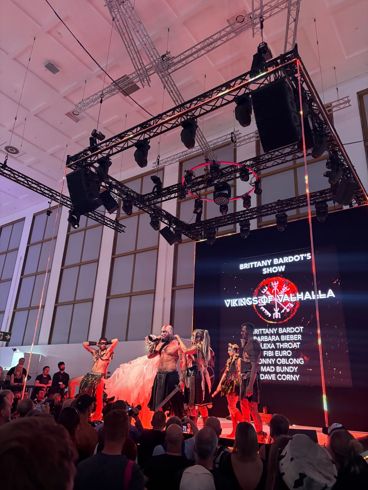 Espectáculo «Vikings of Valhalla» en Venus 2025: artistas con trajes vikingos ante una pantalla LED con la lista del reparto y el público delante
