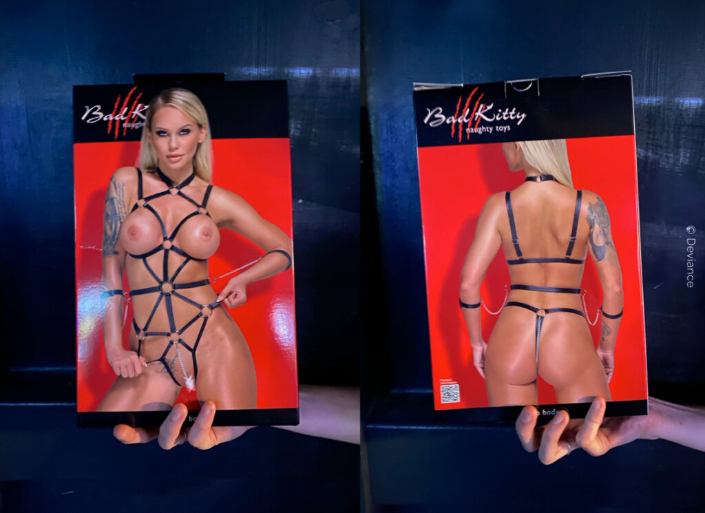 Die Verpackung des Body Harness ist zu sehen. Das Modell und die enthaltenen Handfesseln sind auf der Box abgebildet.