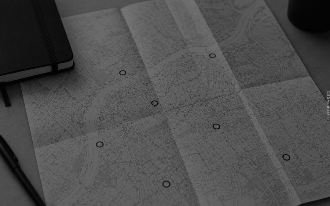 Monochrome Karte auf einem Schreibtisch mit markierten Orten und dunklen Accessoires als Symbolbild für Deviance Places und das Entdecken kinky Locations.